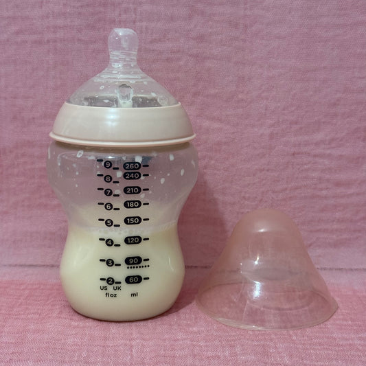 Baby bottle with measurements on a pink background