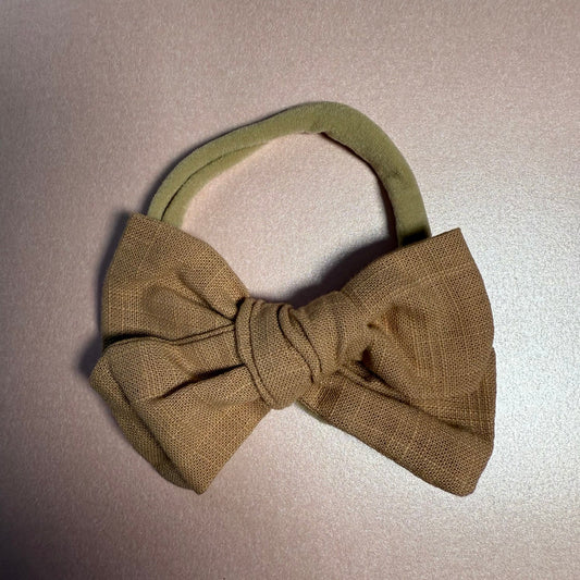 Brown bow headband on a light pink background