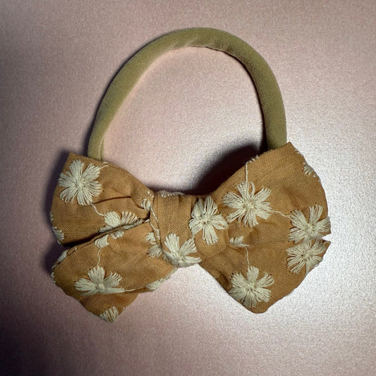 Brown floral bow headband on a light pink background